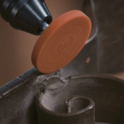 Lixadora elétrica com disco abrasivo laranja a lixar peça metálica curva