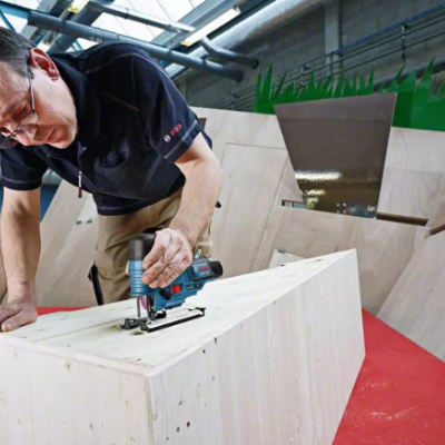 Homem a usar ferramenta elétrica para cortar madeira em ambiente industrial