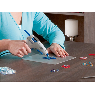 Pessoa com pistola de cola quente a fazer artesanato com contas coloridas