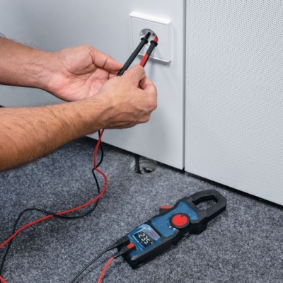 Multímetro digital a medir corrente numa tomada elétrica