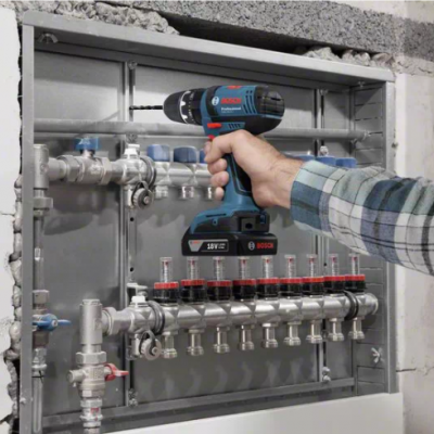 Sonda de misturador a bateria BOSCH azul a ser usada numa caixa metálica embutida com canos de metal