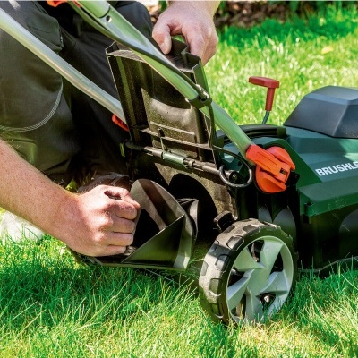 Pessoa ajustando cortador de relva Metabo preto e verde na relva