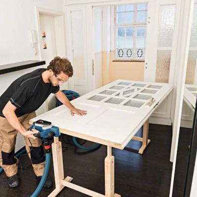 Homem a trabalhar numa porta branca com ferramenta elétrica