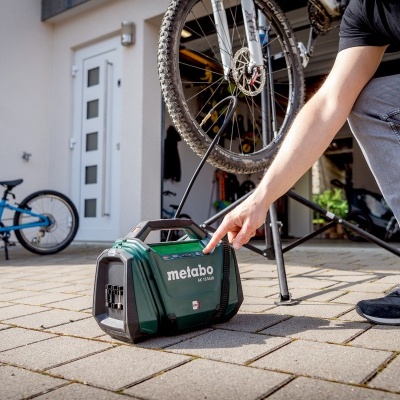 Gerador portátil Metabo verde junto a bicicletas em garagem exterior