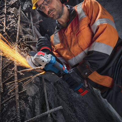 Homem com equipamento de proteção a usar rebarbadora a cortar ferro enferrujado