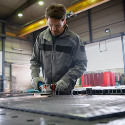 Homem a usar esmeril angular numa chapa de metal numa oficina industrial