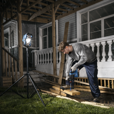 Pessoa a trabalhar com ferramenta elétrica de madeira de noite, usando proteção, sob luz LED