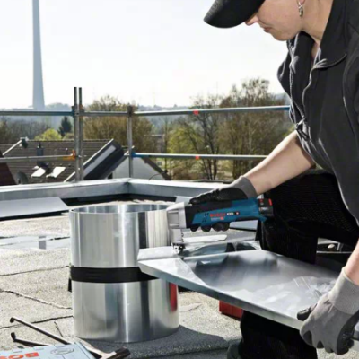 Pessoa a usar ferramenta elétrica num telhado a trabalhar com chapas metálicas
