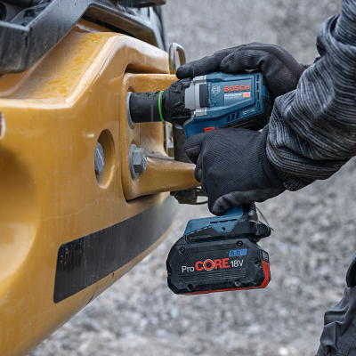Pessoa usando chave de impacto Bosch com bateria ProCORE numa máquina amarela.