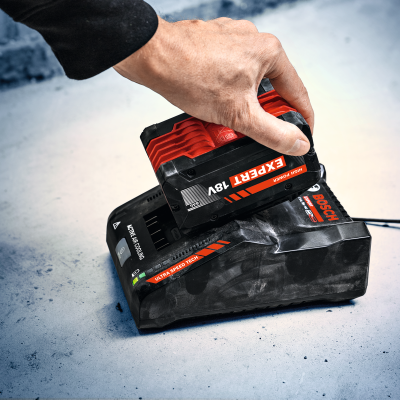 Carregador de bateria Bosch negro e vermelho com bateria EXPERT 18V numa superfície cinzenta