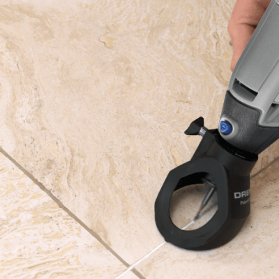Ferramenta elétrica Dremel sendo usada numa superfície de azulejo beige.
