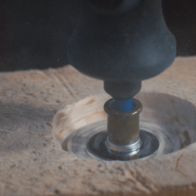 Máquina rotativa a cortar pedra clara com pó e lascas ao redor