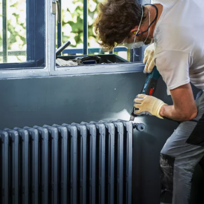 Homem a trabalhar num aquecedor cinzento junto a janela azul