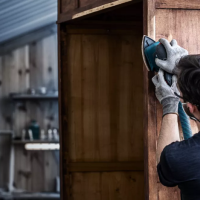 Homem a lixar uma porta de madeira numa oficina