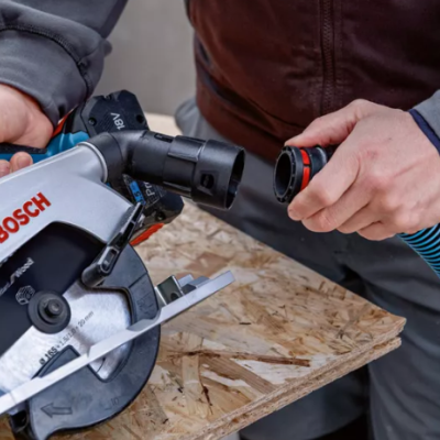 Serra circular Bosch em uso com mangueira de aspiração sobre madeira.