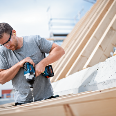 Homem a usar furadeira numa estrutura de madeira em obra