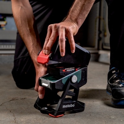 Dispositivo a laser Metabo preto com detalhes em vermelho e cinzento segurado no chão