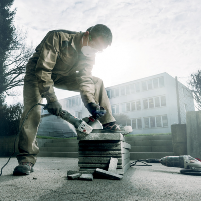 Homem a cortar pedras com serra elétrica em ambiente exterior