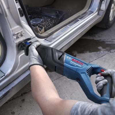 Serra tico-tico Bosch a cortar a porta de um carro prateado