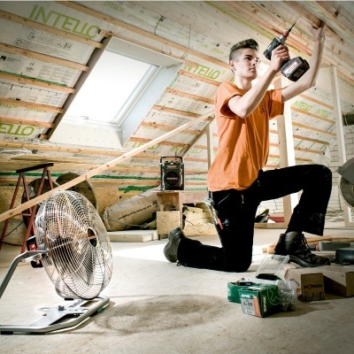 Homem a usar furadeira num sótão em construção com isolamento INTELLO
