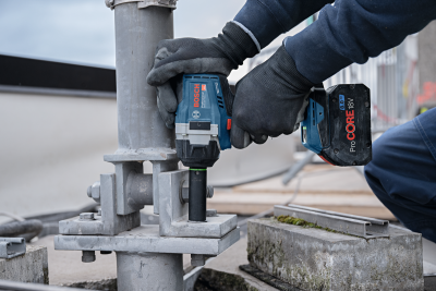 Parafusadeira Bosch sem fios a apertar parafuso em suporte metálico cinza ao ar livre