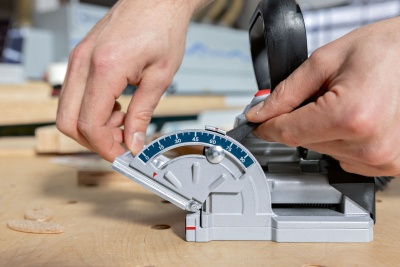 Serra de esquadria cinza com escala azul a medir corte numa peça de madeira