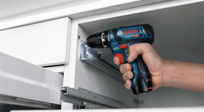 Parafusadeira BOSCH Professional preta e azul sendo usada em cozinha branca moderna