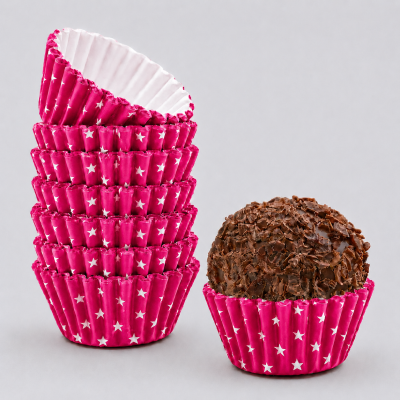 Forminhas de papel rosa com estrelas brancas e brigadeiro com granulados de chocolate