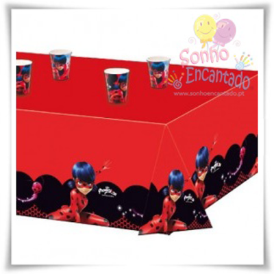 Toalha de mesa vermelha com personagem Ladybug em preto e vermelho e copos de plástico com mesma decoração