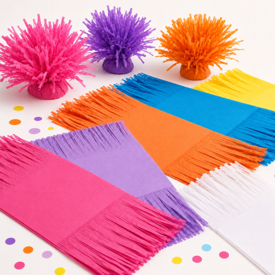 Decorações festivas coloridas em papel frisado e franjas sobre mesa branca com confetes