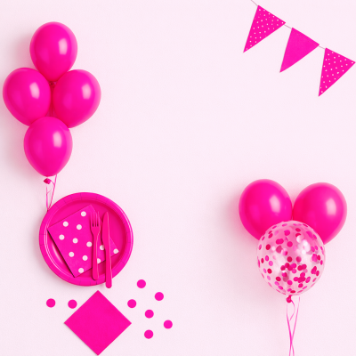 Decoração de festa cor-de-rosa com balões, pratos de papel, guardanapos com bolinhas, talheres e bandeirolas.
