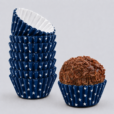 Forminhas de cupcake azuis com estrelas brancas empilhadas junto a doce com lascas de chocolate