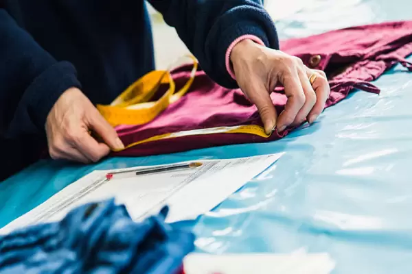 Desenvolvimento Mãos a dobrar tecido amarelo e vermelho com padrão numa mesa de trabalho