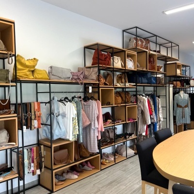 Estante com bolsas, sapatos e roupa feminina num ambiente moderno