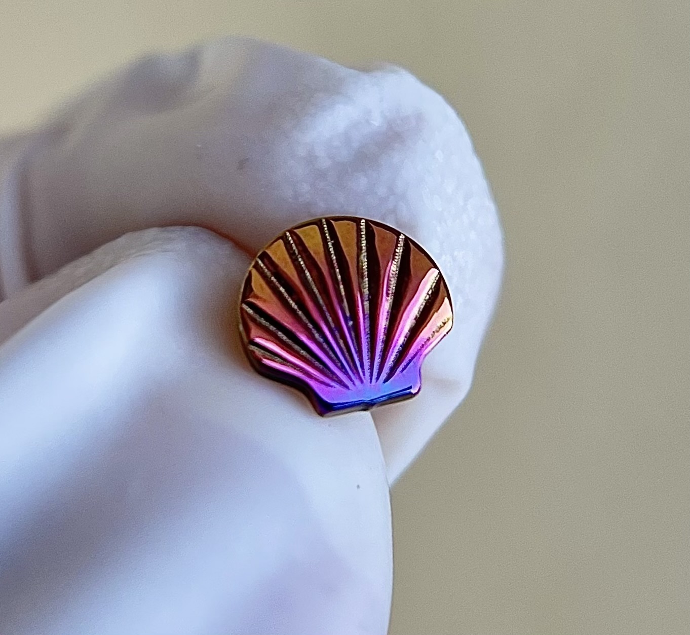 Brinco em forma de concha em metal iridescente com luva branca