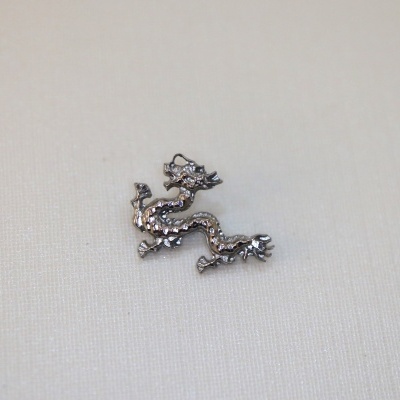 Adorno metálico prateado em forma de dragão sobre fundo branco