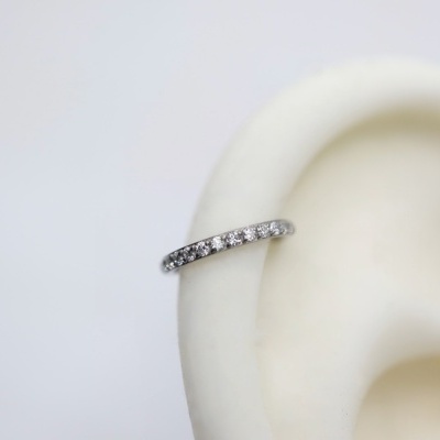 Anel prateado com pedras numa orelha de manequim branca