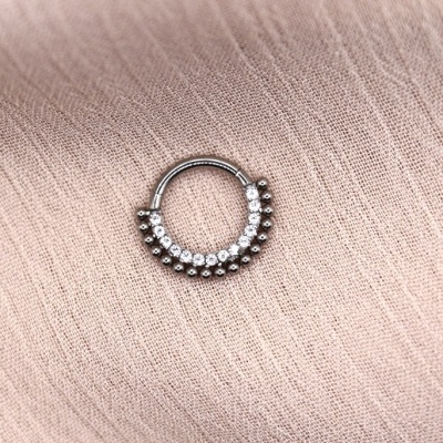 Argola metálica com pedras sobre tecido bege claro texturizado