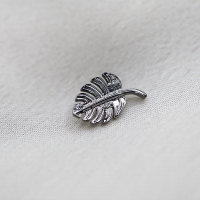 Pingente de folha de metal prateado sobre tecido branco