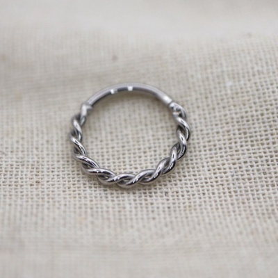 Anel torcido de metal prateado sobre tecido de linho bege