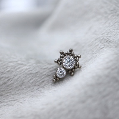 Brinco prateado com pedras redondas sobre tecido cinzento macio