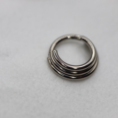 Argola de metal prateado com design de três linhas paralelas sobre fundo branco