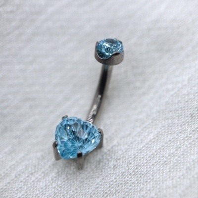 Piercing para umbigo com pedras azuis sobre tecido branco