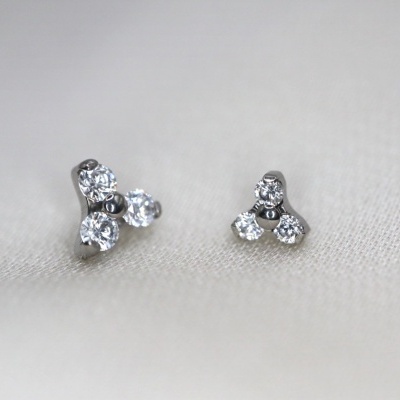 Brincos pequenos de prata com pedras brilhantes sobre tecido claro