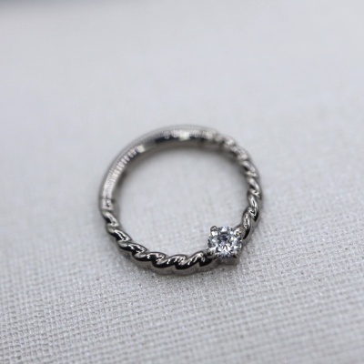 anel prata com pedra brilhante sobre tecido cinza claro