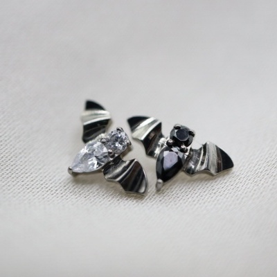 Brincos com pedras pretas e cristal em base metálica prateada sobre tecido branco