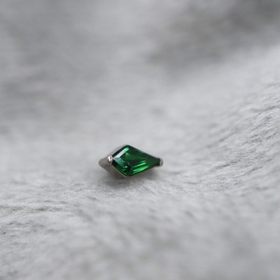 Pendente ou brinco pequeno com pedra verde facetada sobre superfície branca