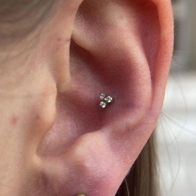 Piercing na hélice da orelha com três pedras cristalinas pequenas