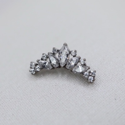 Brinco ou piercing prateado com pedras brilhantes em tecido bege