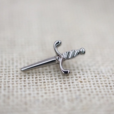 Brinco em forma de espada prateada sobre tecido bege